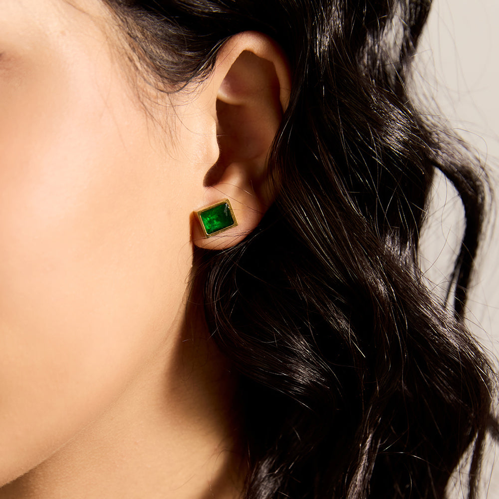 Model wearing Aveera designer gold plated emerald green square stud earring, showcasing minimalist style.