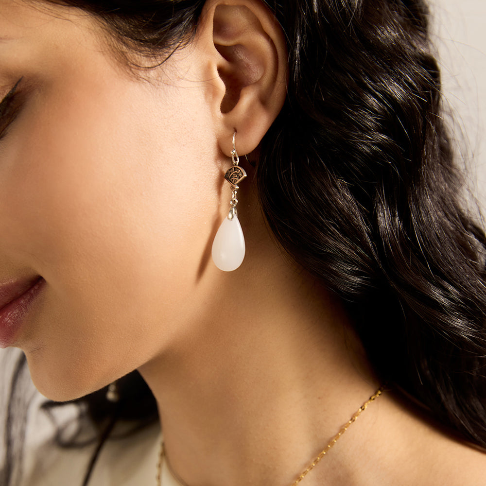 Close-up of model wearing Aveera designer filigree fan white jade drop earring, highlighting intricate design and teardrop shape.