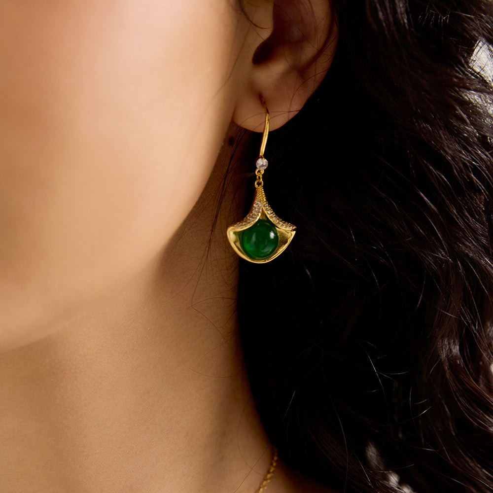 Close-up of model wearing Aveera designer gold plated ginkgo green gem drop earring, highlighting vibrant green stone and sparkle.