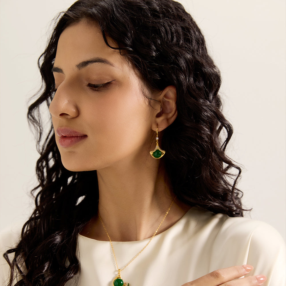 Model wearing Aveera designer gold plated ginkgo green gem drop earrings and matching necklace, elegant full look.