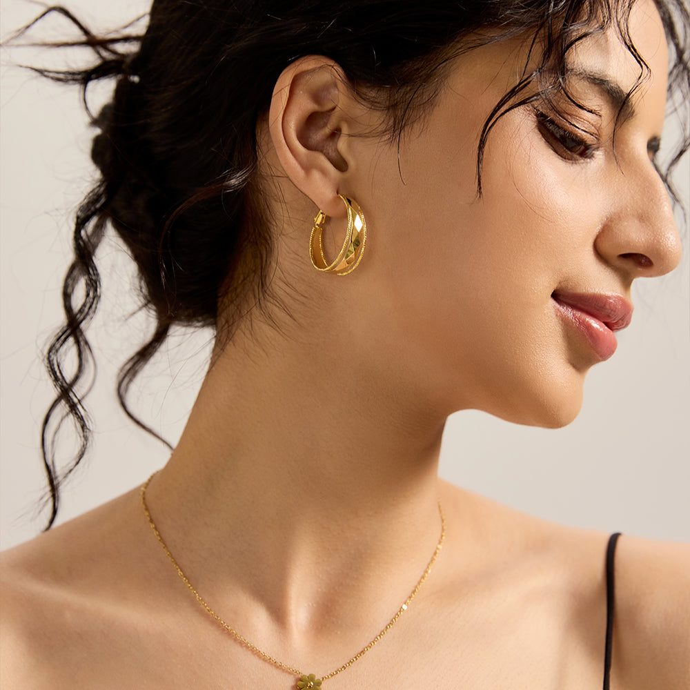 Close-up of model wearing Aveera designer gold plated textured oval hoop earring, highlighting the unique surface texture.