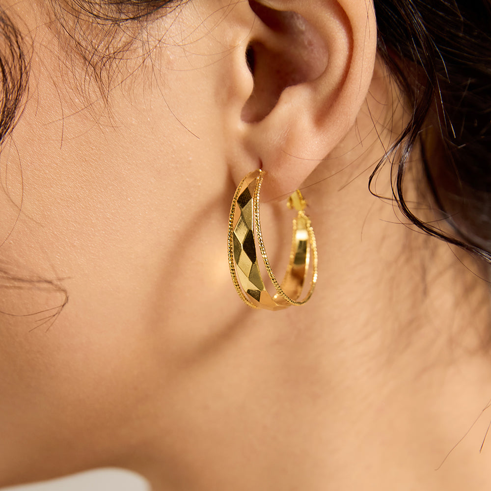 Model wearing Aveera designer gold plated textured oval hoop earring, showcasing unique design and comfortable fit.

