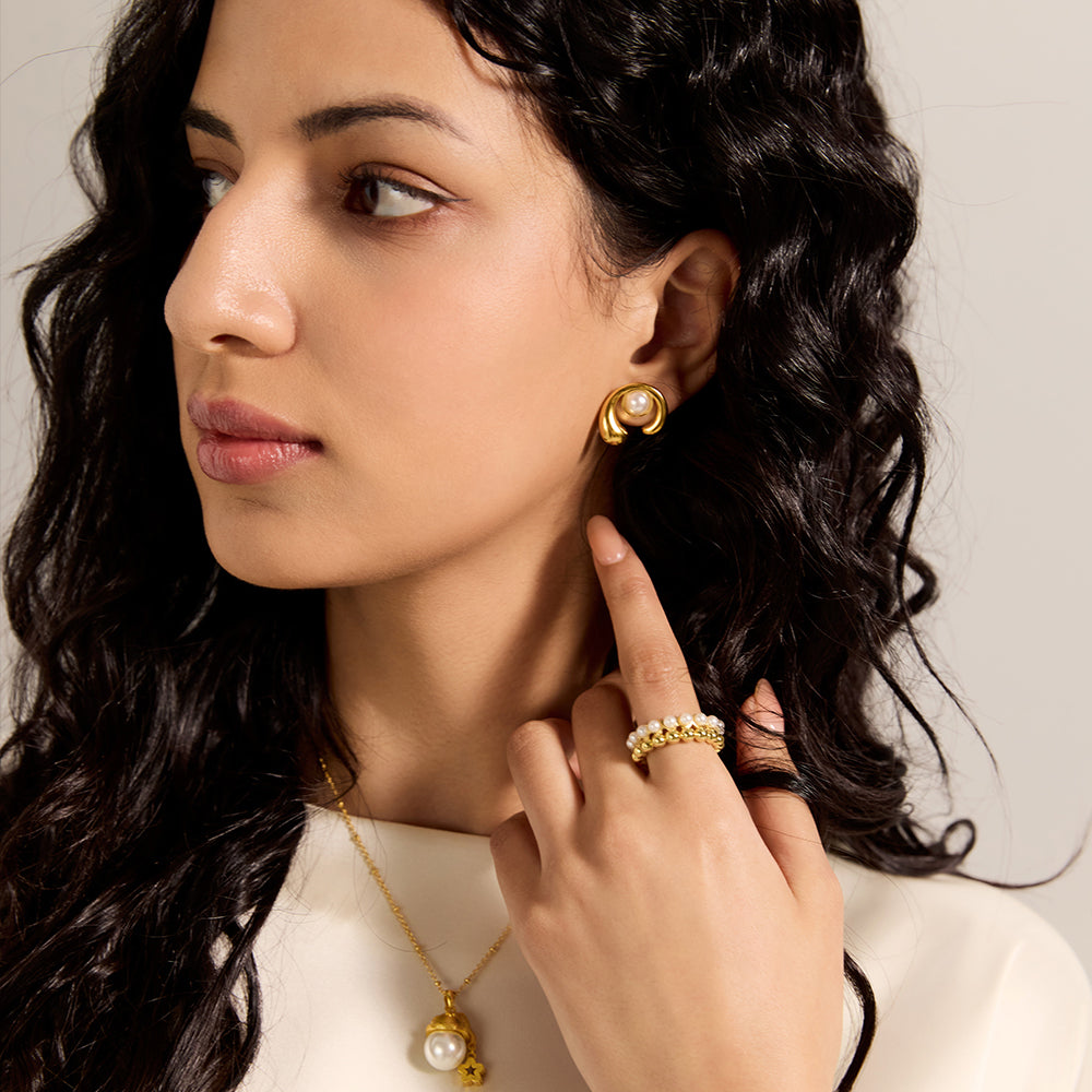Close-up of Aveera designer gold tone crossover ring, highlighting its intricate intertwined bands.

