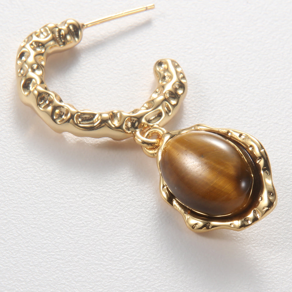 Close-up of Aveera designer hammered gold plated half hoop earring showing textured surface and natural tiger eye gemstone.