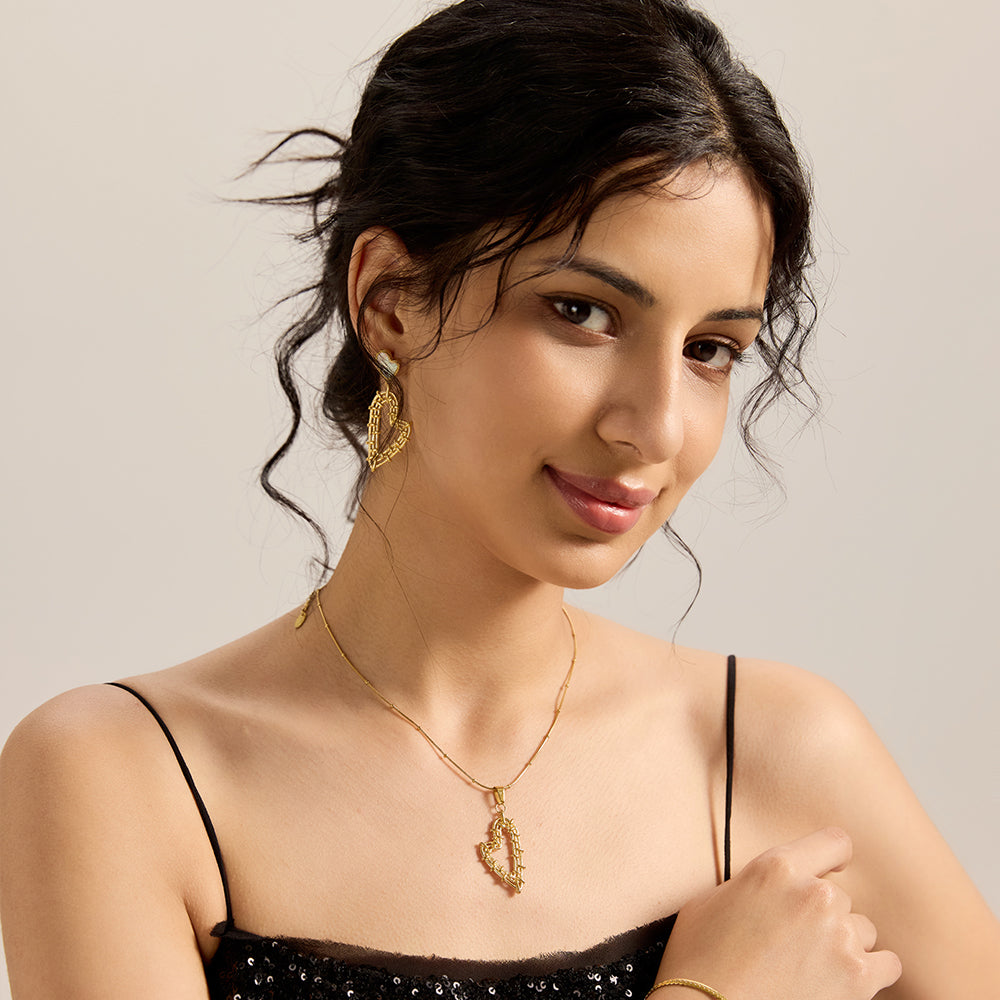 Full shot of model wearing Aveera designer gold plated hollow heart mother of pearl drop earrings, showcasing overall fashion style.