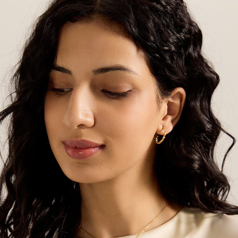 Close-up of Aveera designer serpent pearl earring showing intricate textured snake body, green gem eyes, and luminous pearl.