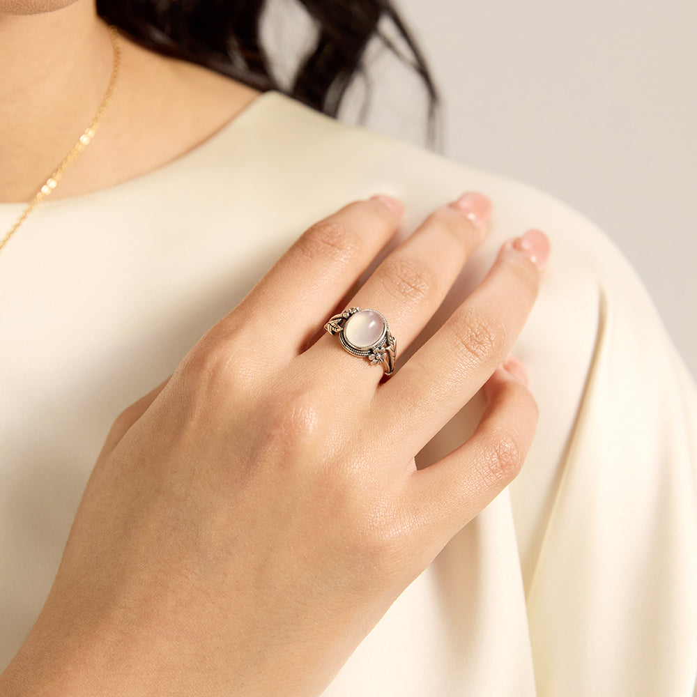Model wearing Aveera designer silver tone oval luminous white stone floral engraved ring, showcasing its elegant profile.