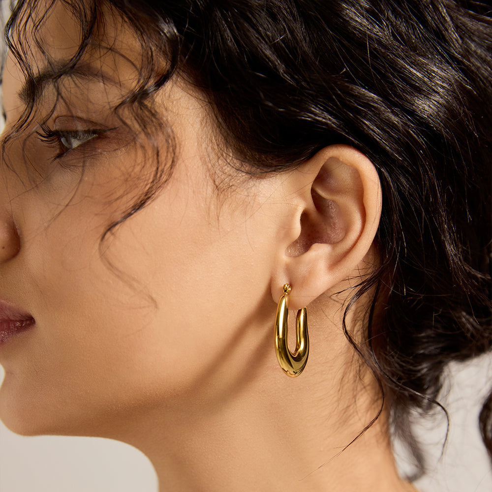 Model wearing Aveera designer gold plated twisted hoop earring, showcasing minimalist style.