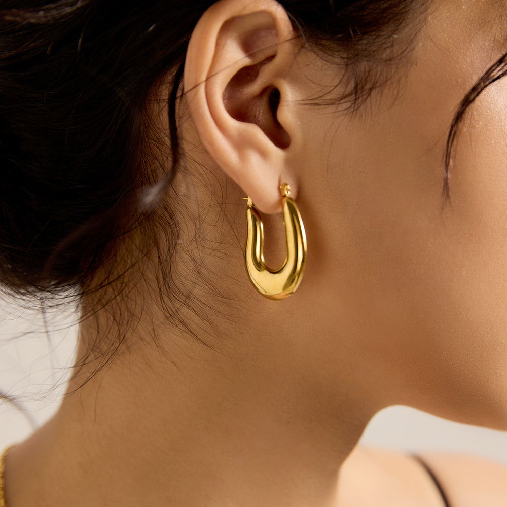 Close-up of model wearing Aveera designer gold plated twisted hoop earring, highlighting texture and shine.