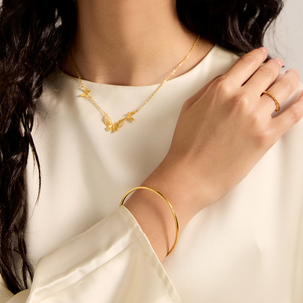 Model showcasing Aveera gold tone minimalist closed bangle bracelet with upper body outfit, highlighting its versatile and refined style.