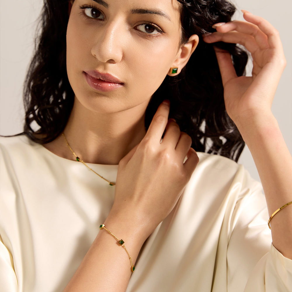 Another view of model wearing Aveera gold tone dainty bracelet with green gemstones, accentuating its subtle charm.