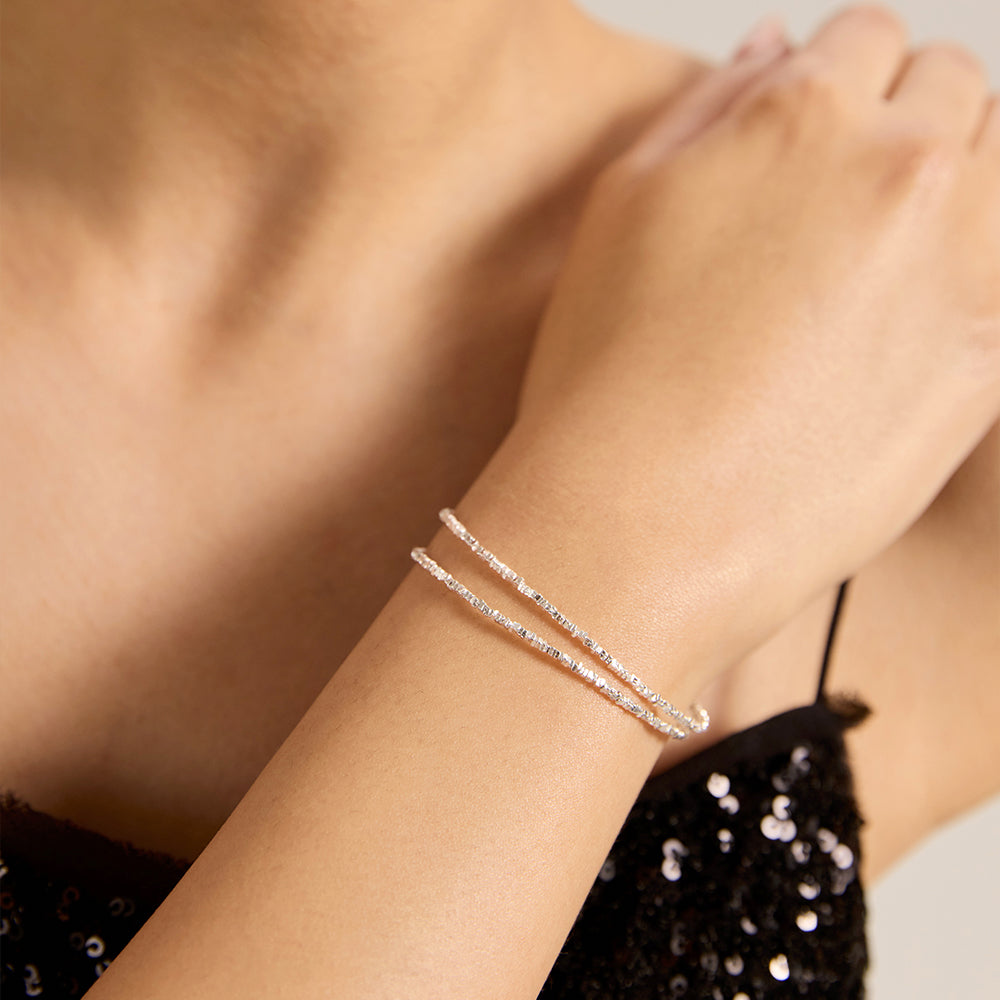 Close-up of model wearing Aveera silver tone shimmering pave chain adjustable bracelet on wrist, showcasing its delicate sparkle.
