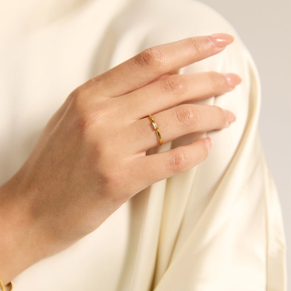 Close-up of a woman's hand wearing a gold tone baguette cut CZ ring, showcasing its fit and sparkle.