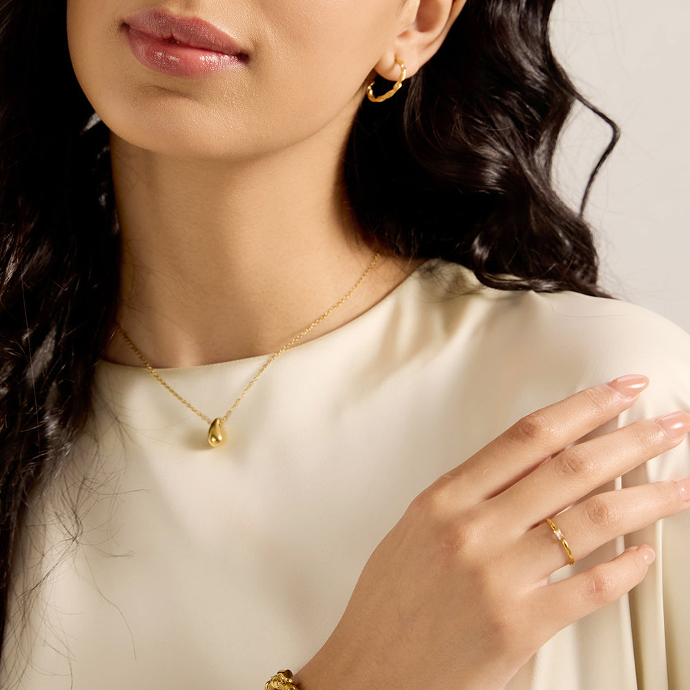 Woman wearing a gold tone baguette cut CZ ring, highlighting its minimalist elegance on the hand.