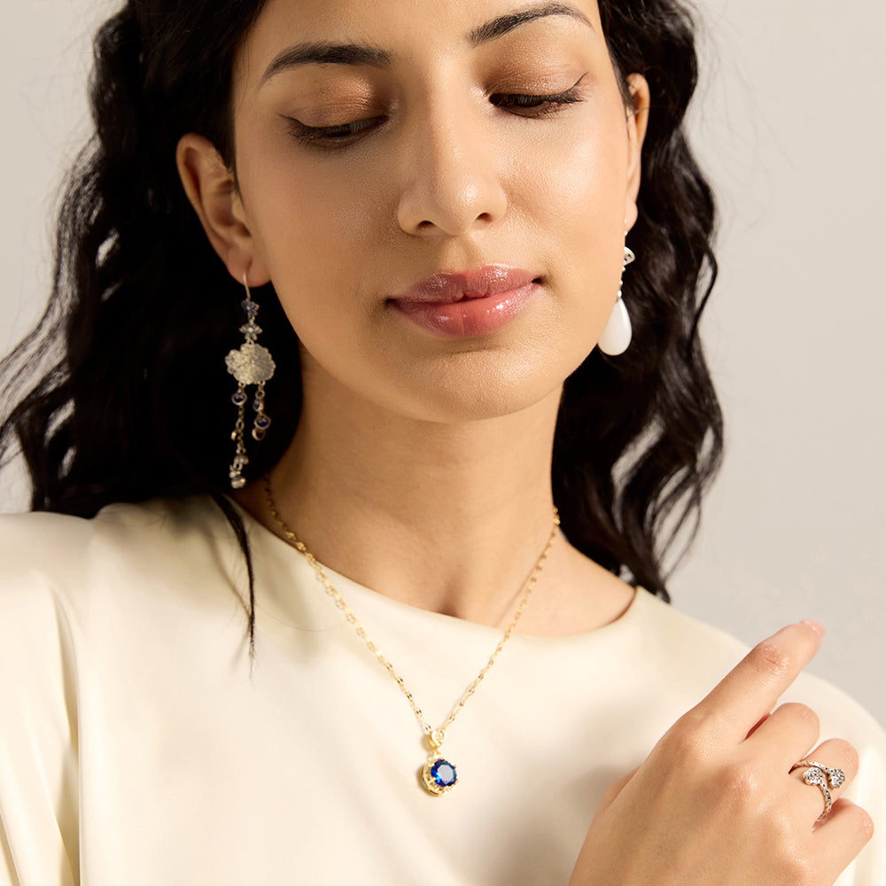 Woman modeling gold tone blue sapphire disc necklace, showcasing its elegant spiritual appeal and how it enhances overall look.