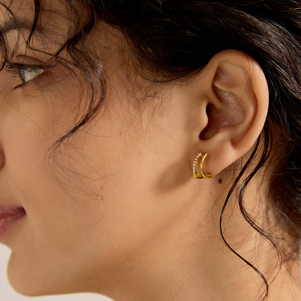 Woman wearing gold tone C-shaped micro pave stud earrings, showcasing overall look and fit.