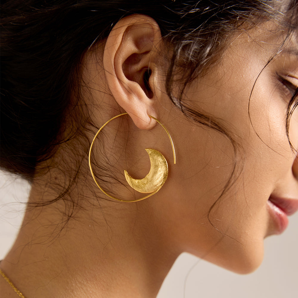 Close-up of woman's ear wearing a gold celestial sun hoop earring, showcasing fit.