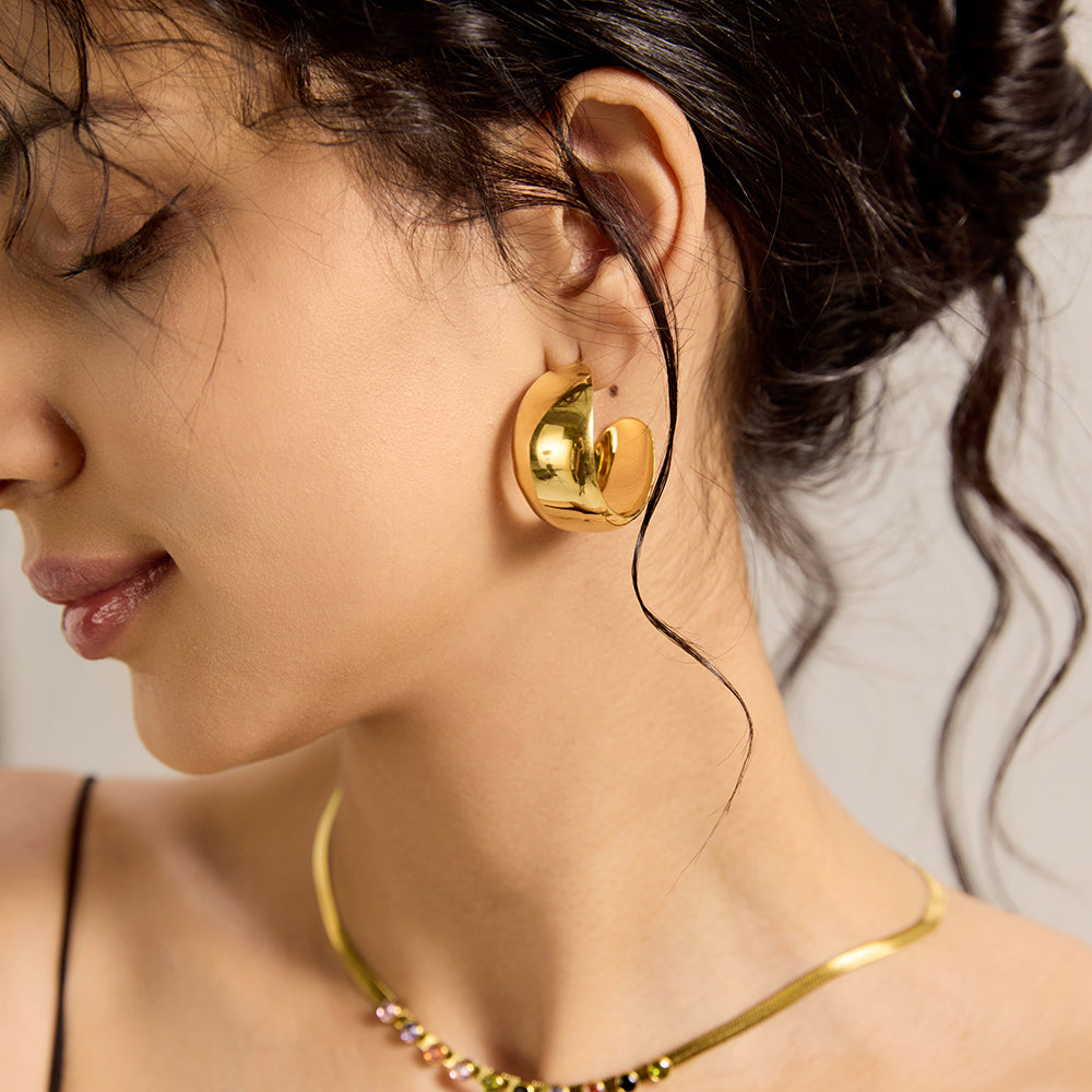 Woman wearing gold chunky dome hoop earrings, showcasing overall style and fit.