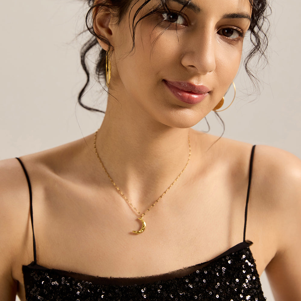 Woman wearing gold tone crescent moon necklace with matching jewelry.