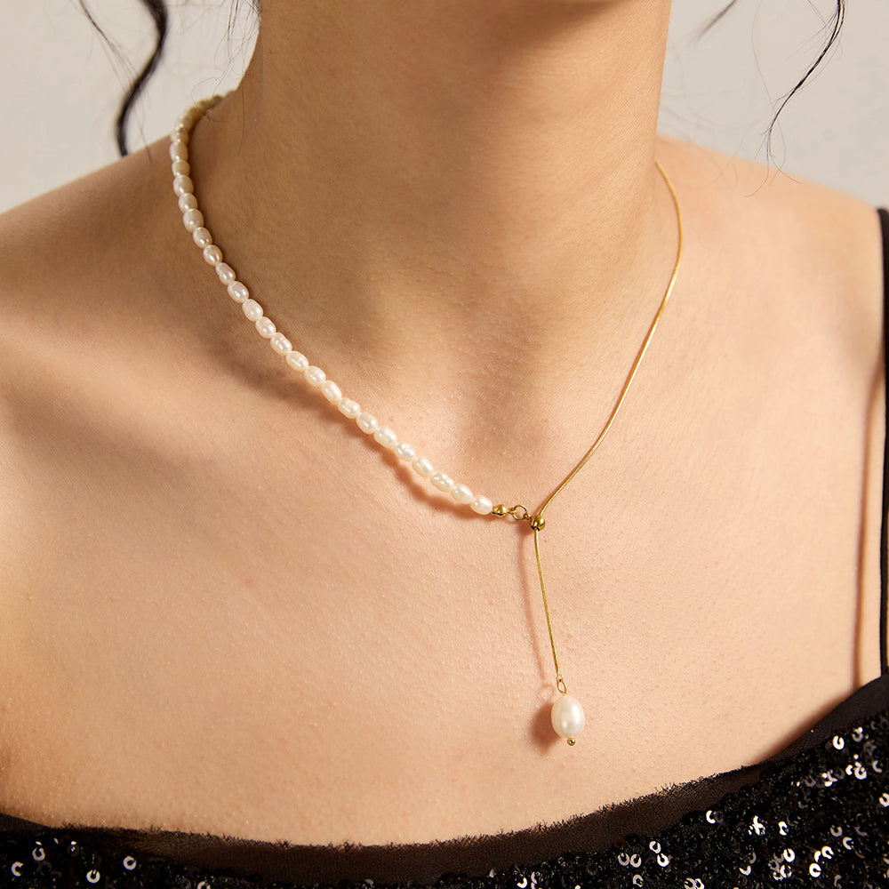 Woman wearing gold tone half pearl and chain lariat necklace, close-up highlighting the design's balance and the dangling pearl.