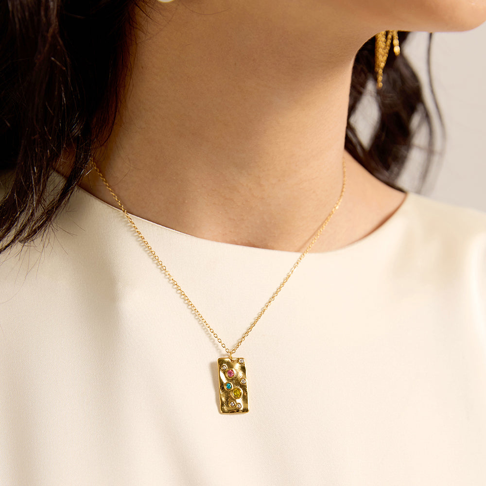 Woman wearing gold tone hammered rectangular energy necklace, close-up showing the unique hammered texture and multi-color chakra crystals.