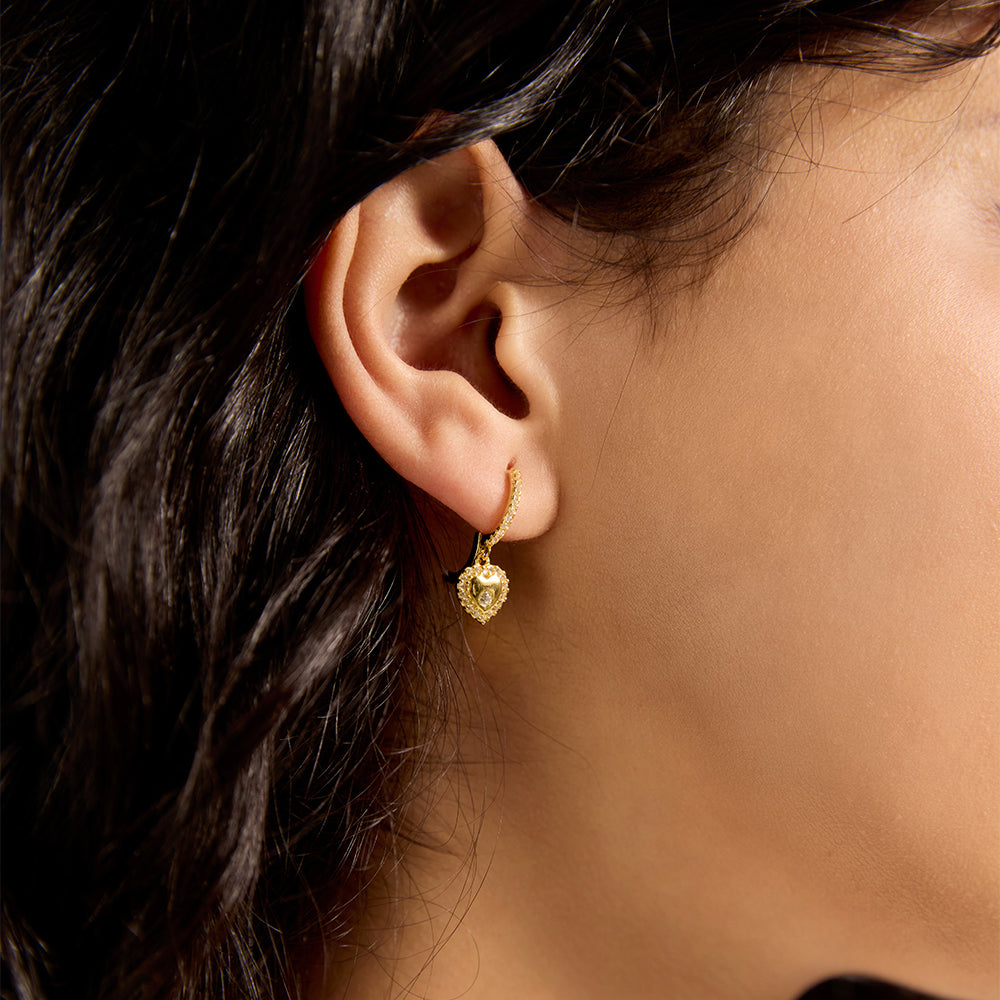Close-up of woman wearing dainty gold heart hoop earrings, showcasing the micro pave detail.