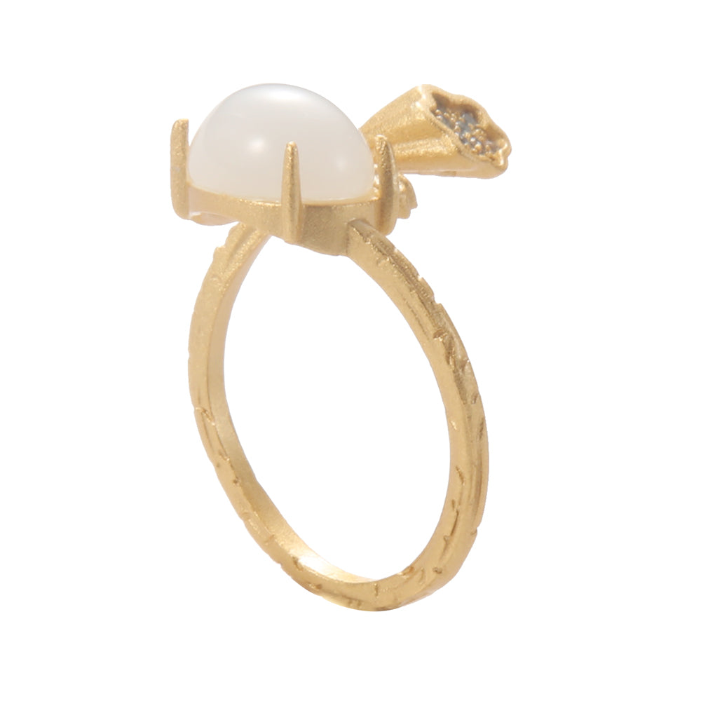 Close-up of gold tone lotus pod ring with white stone, showing intricate details and its spiritual significance.