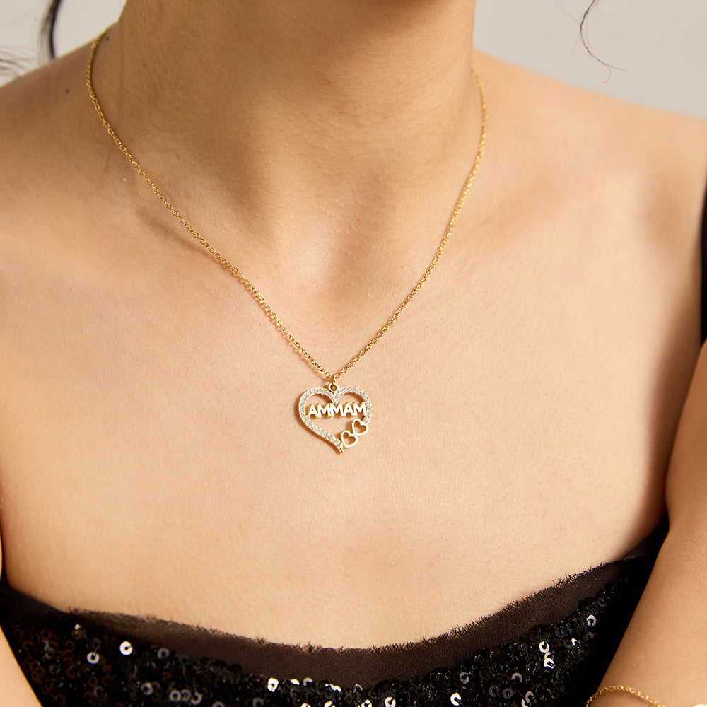 Woman wearing gold tone "MAMMA" heart necklace, showcasing CZ details.