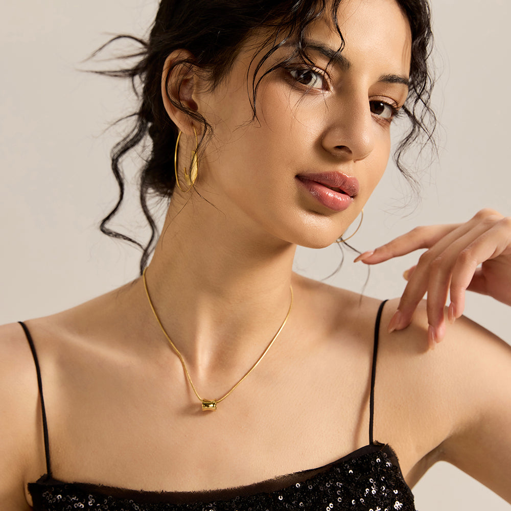 Woman modeling gold tone minimalist tube energy necklace, showcasing its versatile style and spiritual presence.