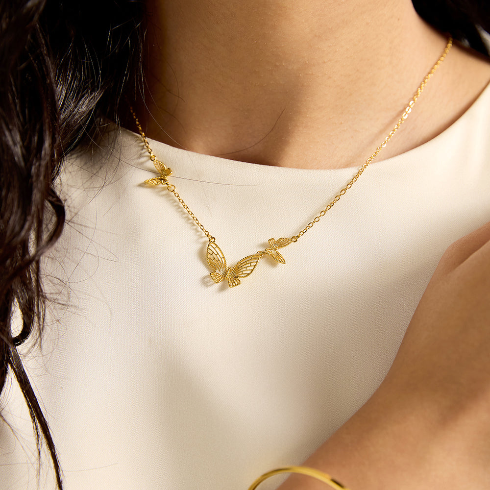 Woman wearing gold tone multi-butterfly charm necklace, close-up showing the intricate butterfly details on the neckline.