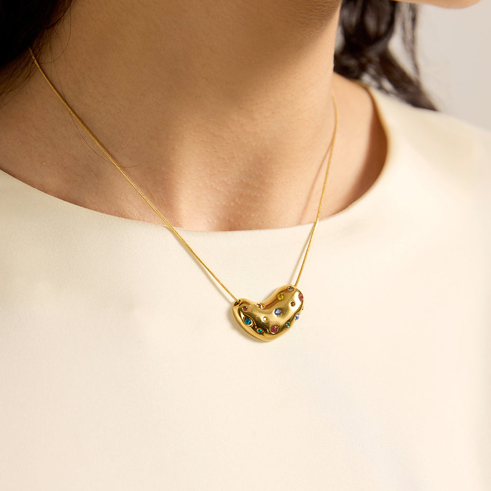 Woman wearing gold tone bean pendant necklace, close-up showing the multi-color crystals and unique shape.