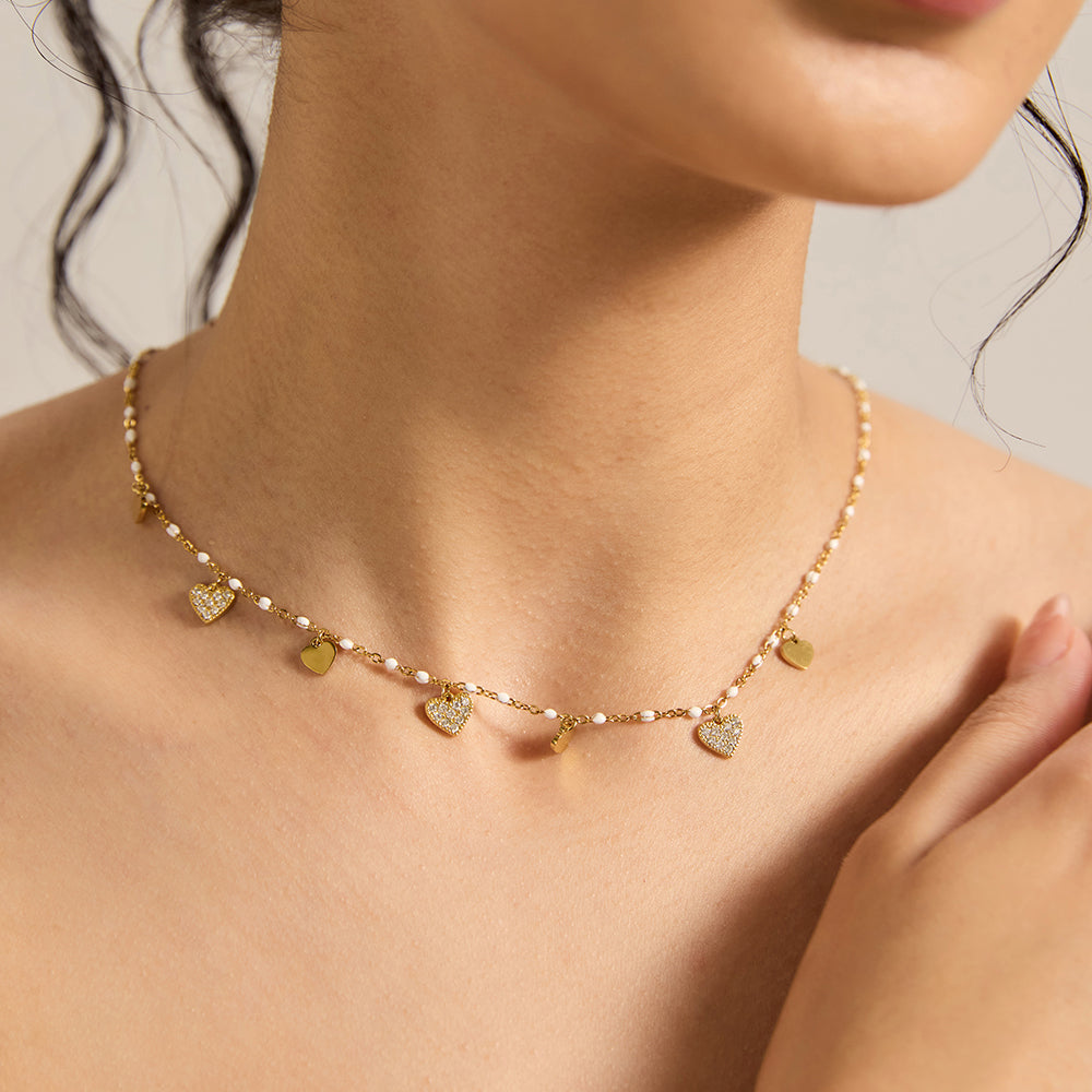 Woman wearing elegant gold tone multi-heart charm necklace, showing detail.