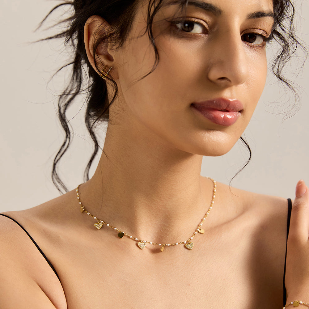 Woman wearing gold tone multi-heart charm necklace with matching bracelet.