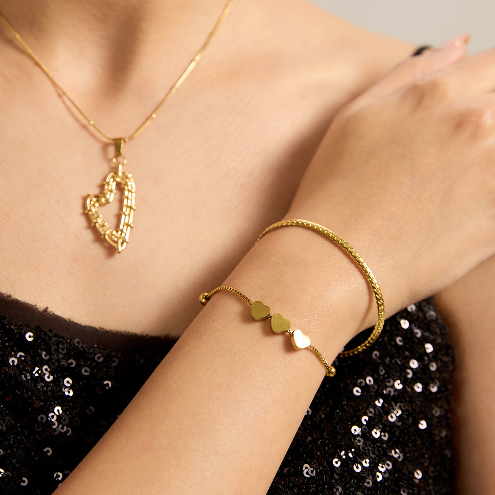 Woman wearing gold tone multi-strand heart bracelet, showcasing layered design.
