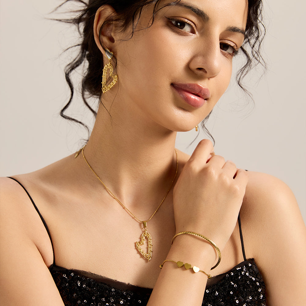 Woman wearing gold tone multi-strand heart bracelet and matching necklace/earrings.