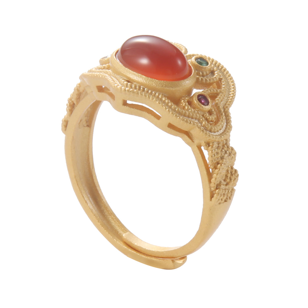Close-up of gold tone ornate ring featuring a red-orange gemstone and intricate filigree details, representing ancient spiritual wisdom.