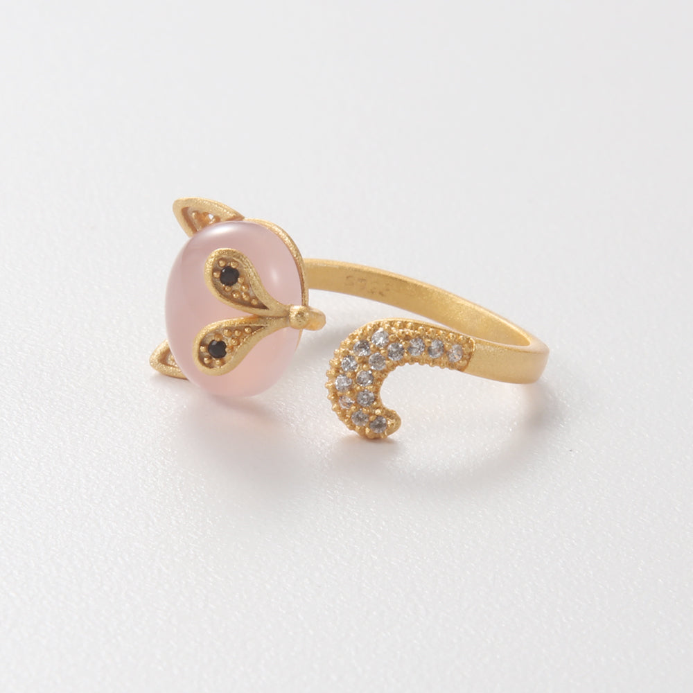 Close-up of gold tone fox ring with pink stone, showing intricate details of the fox's head and the curving pave-set tail.