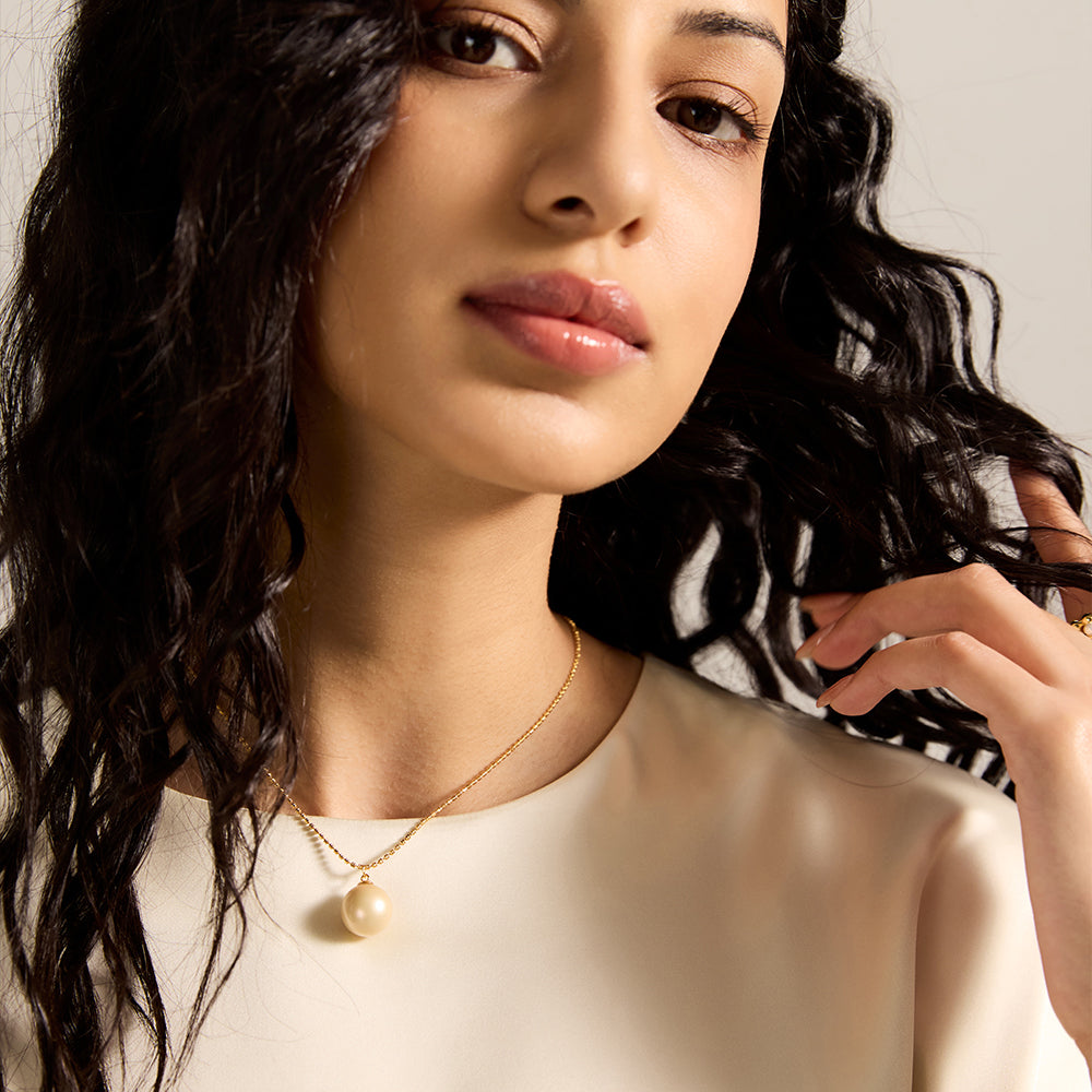 Woman wearing gold tone spherical pearl necklace from another angle, emphasizing its versatile style and connection to inner peace.