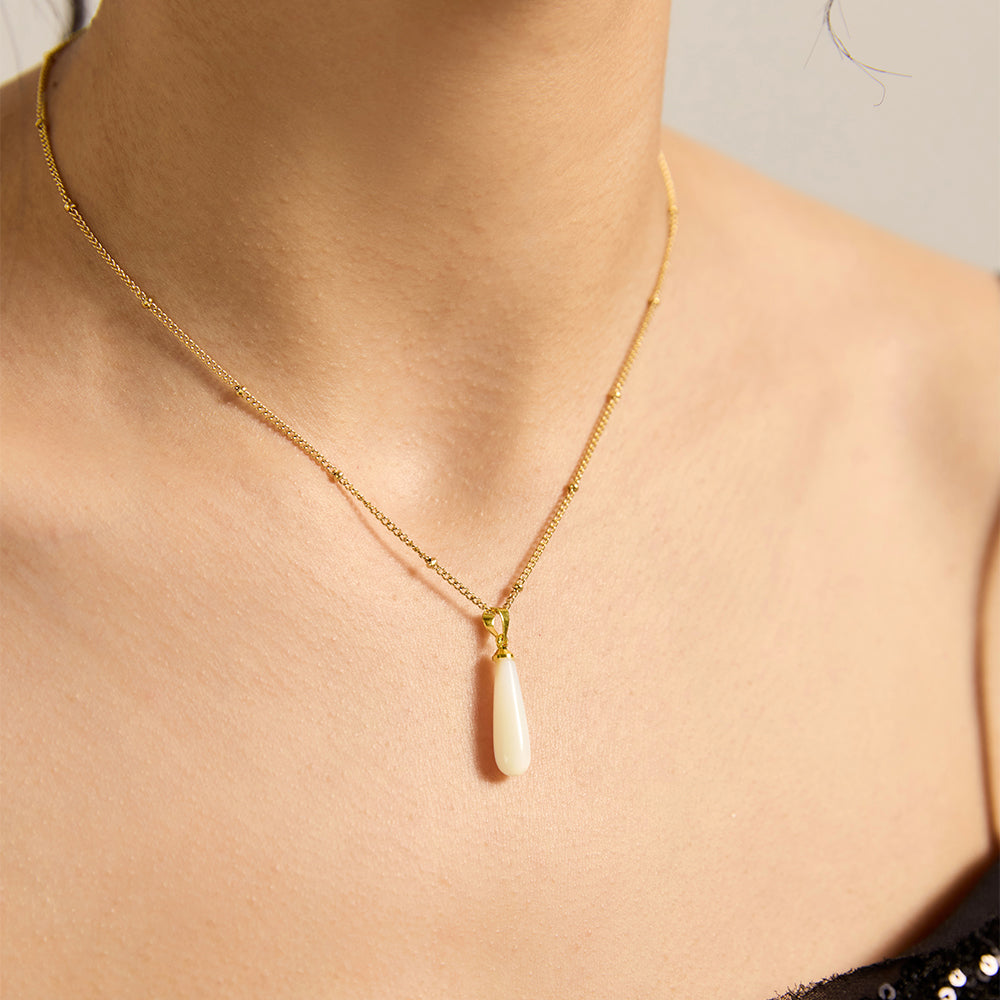 Woman wearing gold tone baroque pearl necklace, close-up showing pearl's unique shape.
