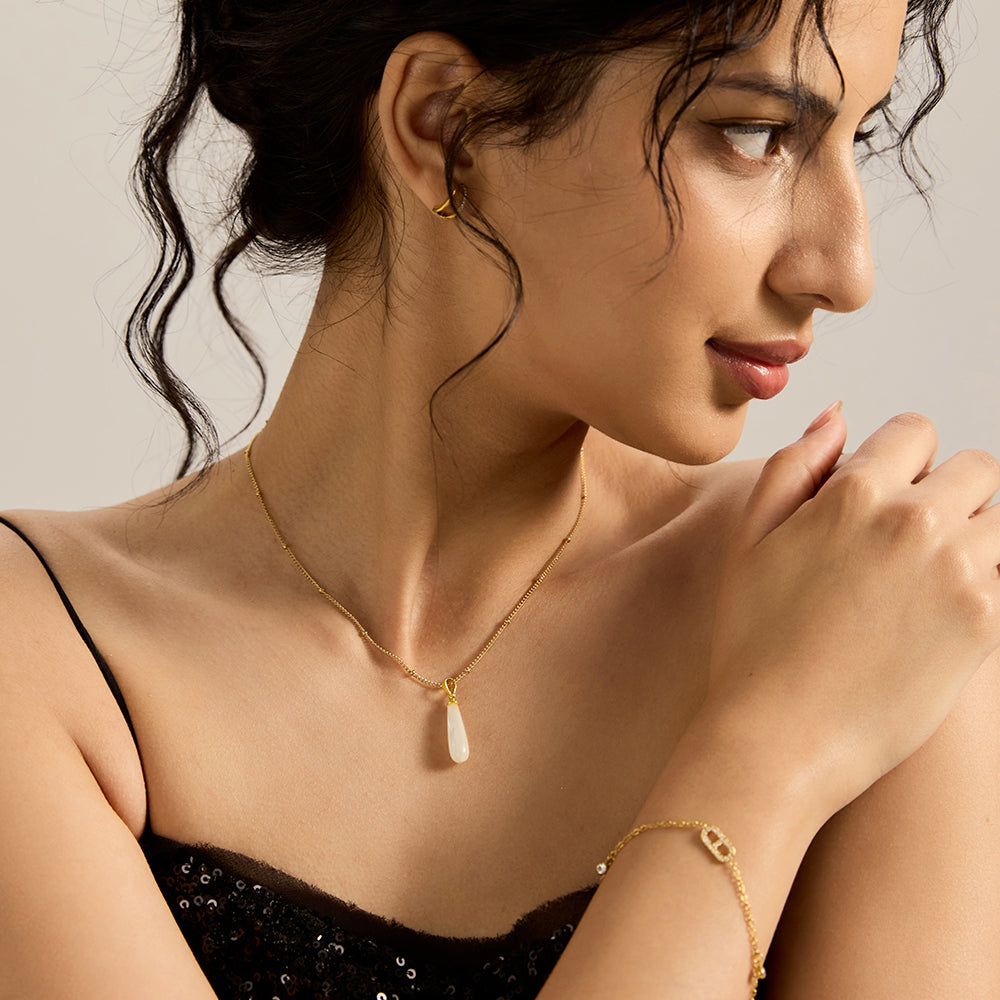 Woman wearing gold tone baroque pearl pendant necklace, showcasing its elegant look.