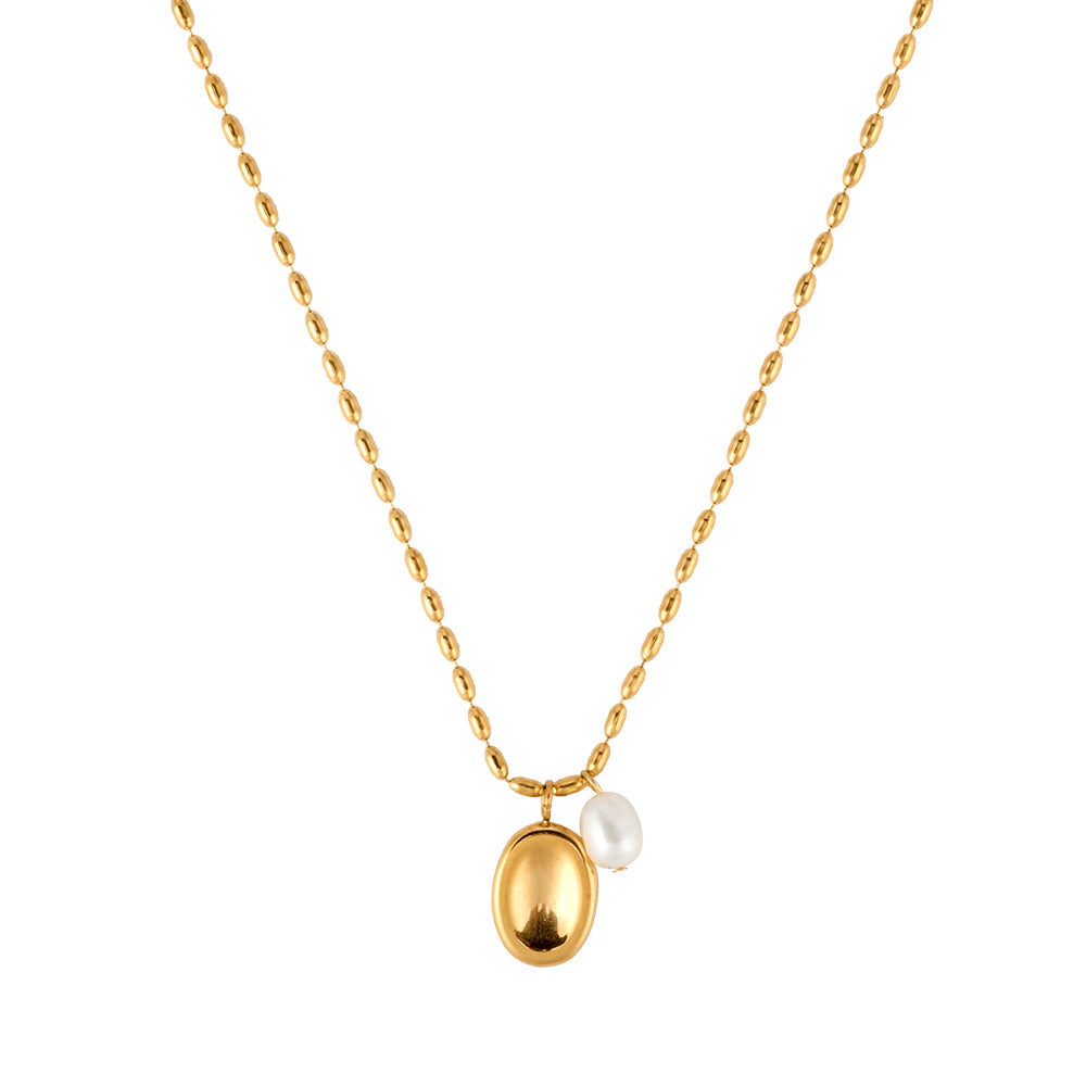 Minimalist gold tone necklace with a small, textured circular disc pendant, flat lay.