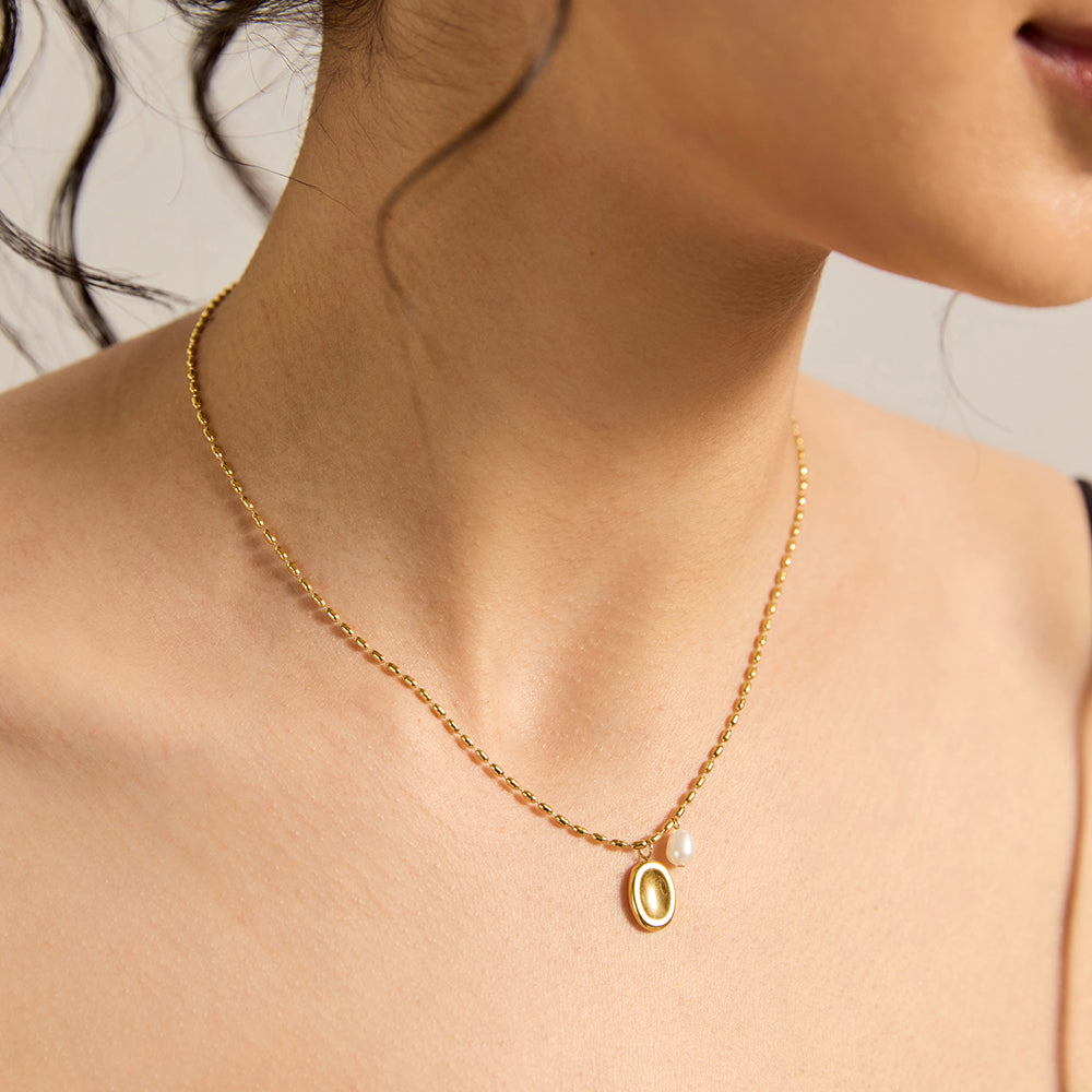 Woman wearing minimalist gold tone textured disc pendant necklace, close-up.