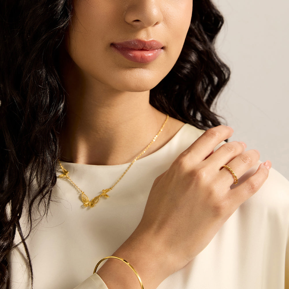 Woman wearing a gold tone textured twist band ring, highlighting its delicate elegance as an everyday accessory.