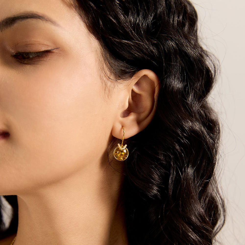 Woman wearing a gold tone amber/yellow-brown gemstone stud earring, showcasing side profile and fit.