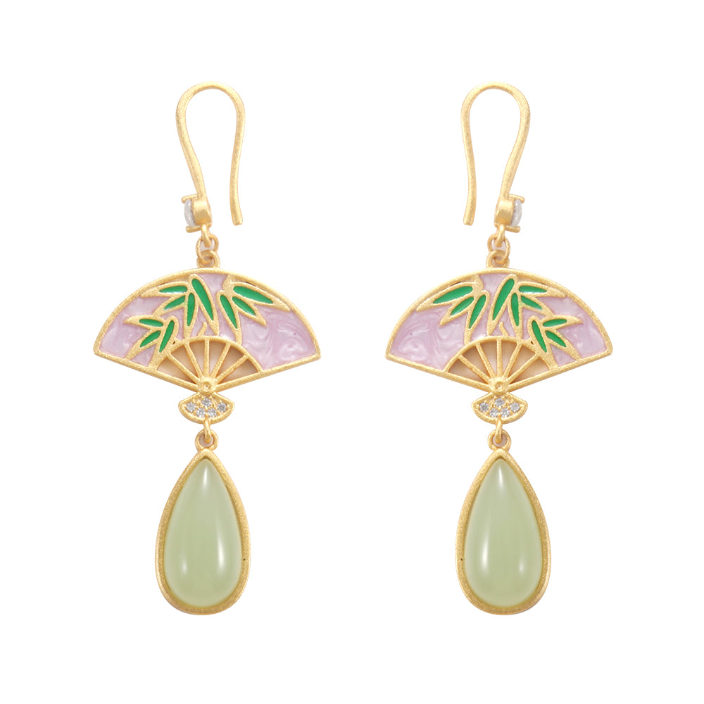 Close-up of gold tone enamel fan and bamboo drop earrings showing intricate enamelwork and gemstone.
