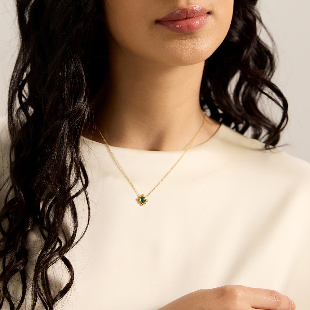 Woman wearing gold tone green stone necklace and matching earrings.