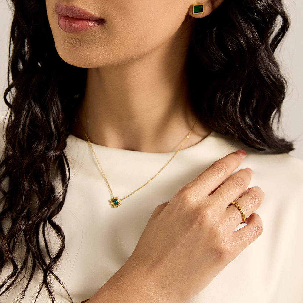 Woman wearing gold tone green stone necklace and matching earrings.