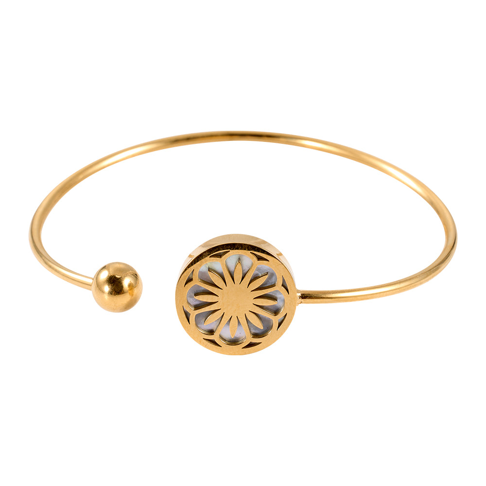 Close-up of gold tone open cuff bangle showing floral motif and ball end.