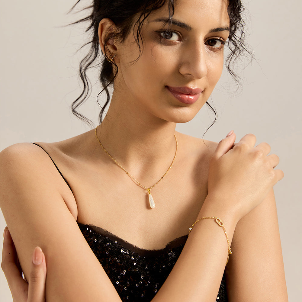 Woman wearing gold tone oval CZ charm bracelet and a matching necklace.