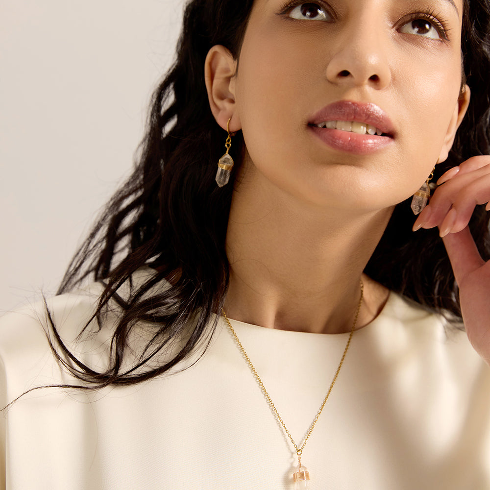 Side view of woman wearing gold thin hoop earrings with wrapped crystal point dangles, emphasizing their organic and spiritual appeal.